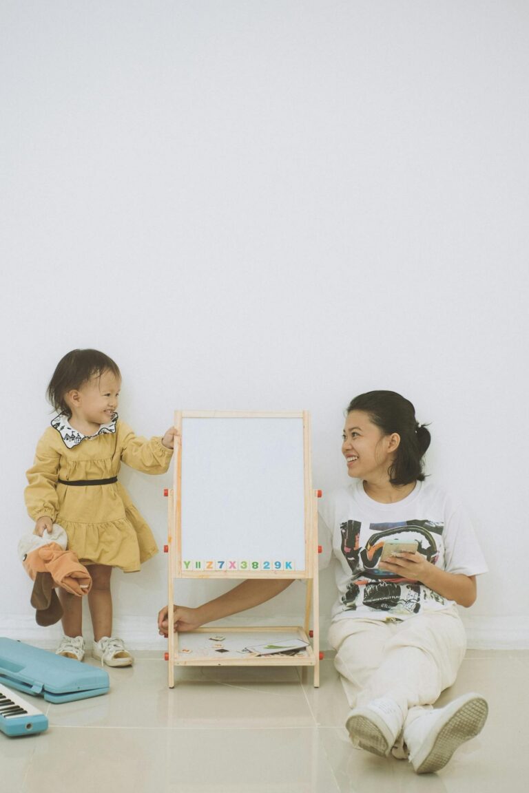 A mother and daughter enjoy a learning moment with a whiteboard indoors.